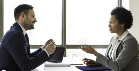 Man and woman across desk from each other conducting an interview.